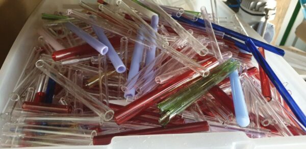 Close-up of a diverse array of colorful borosilicate glass tube offcuts, including red, blue, and clear pieces, ready for various creative and industrial uses.