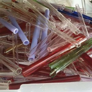 Close-up of a diverse array of colorful borosilicate glass tube offcuts, including red, blue, and clear pieces, ready for various creative and industrial uses.